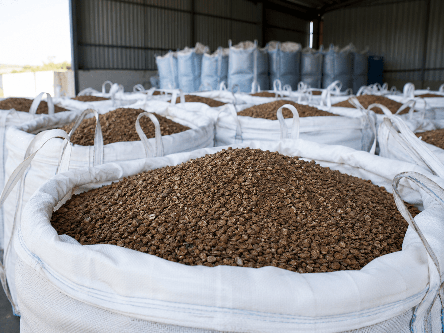 Open Big Bags filled with granulated biomass in a storage shed