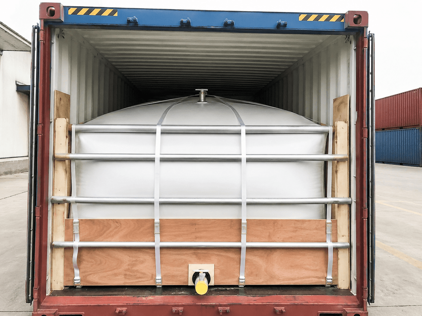 A flexitank liner installed inside a shipping container, held behind a bulkhead
